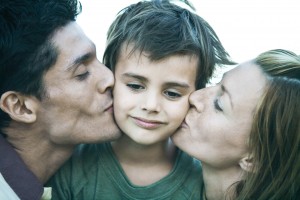 Man and woman kissing son on cheeks, close-up